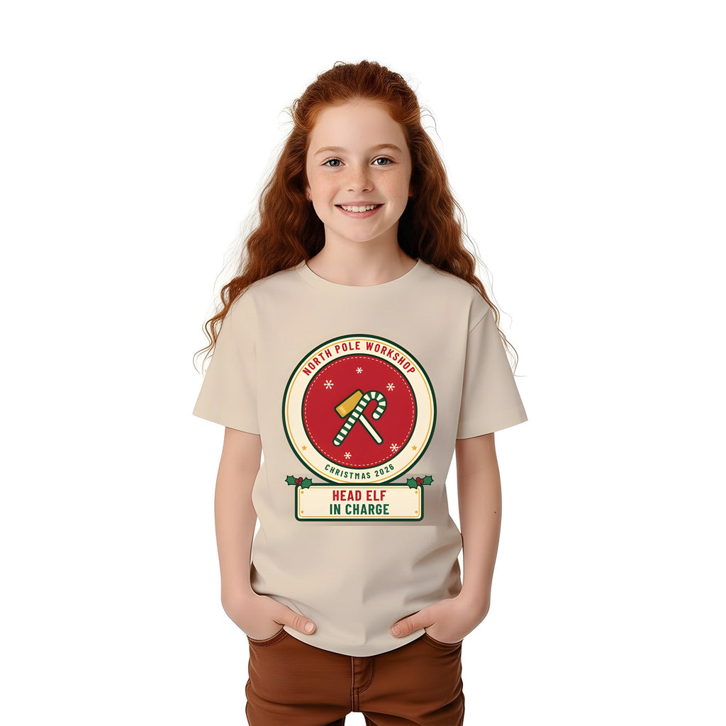 Girl wearing the Build Your Own Badge personalized kids Christmas shirt in Sand, with HEAD ELF IN CHARGE on the name plate
