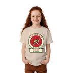 Girl wearing the Build Your Own Badge personalized kids Christmas shirt in Sand, with HEAD ELF IN CHARGE on the name plate